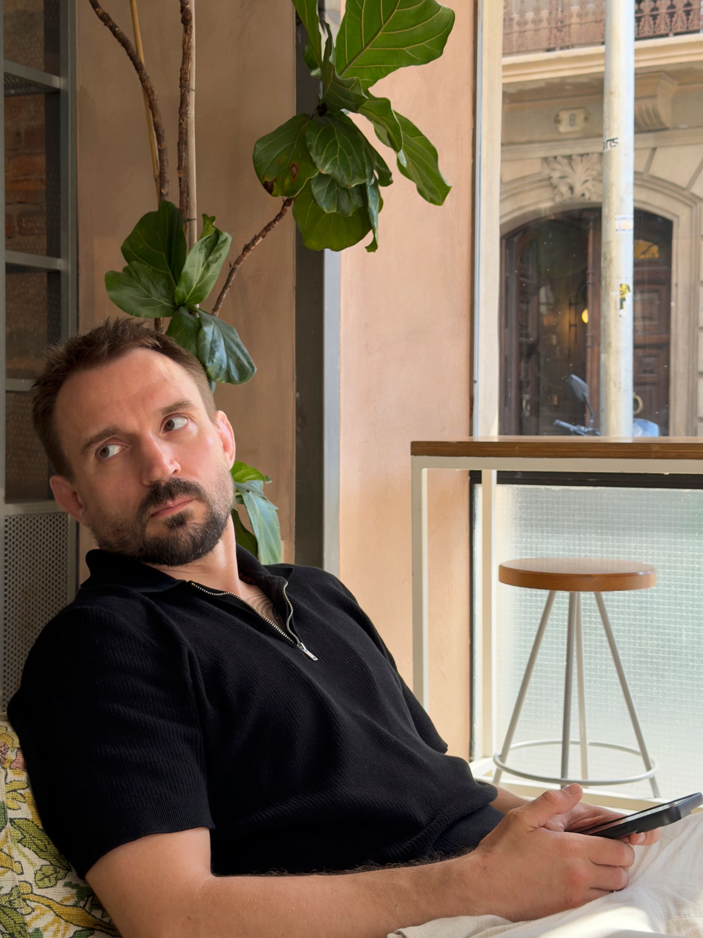 Alexander Lebedev, the retreat's host, sitting by a window in a bright café next to a fig plant.