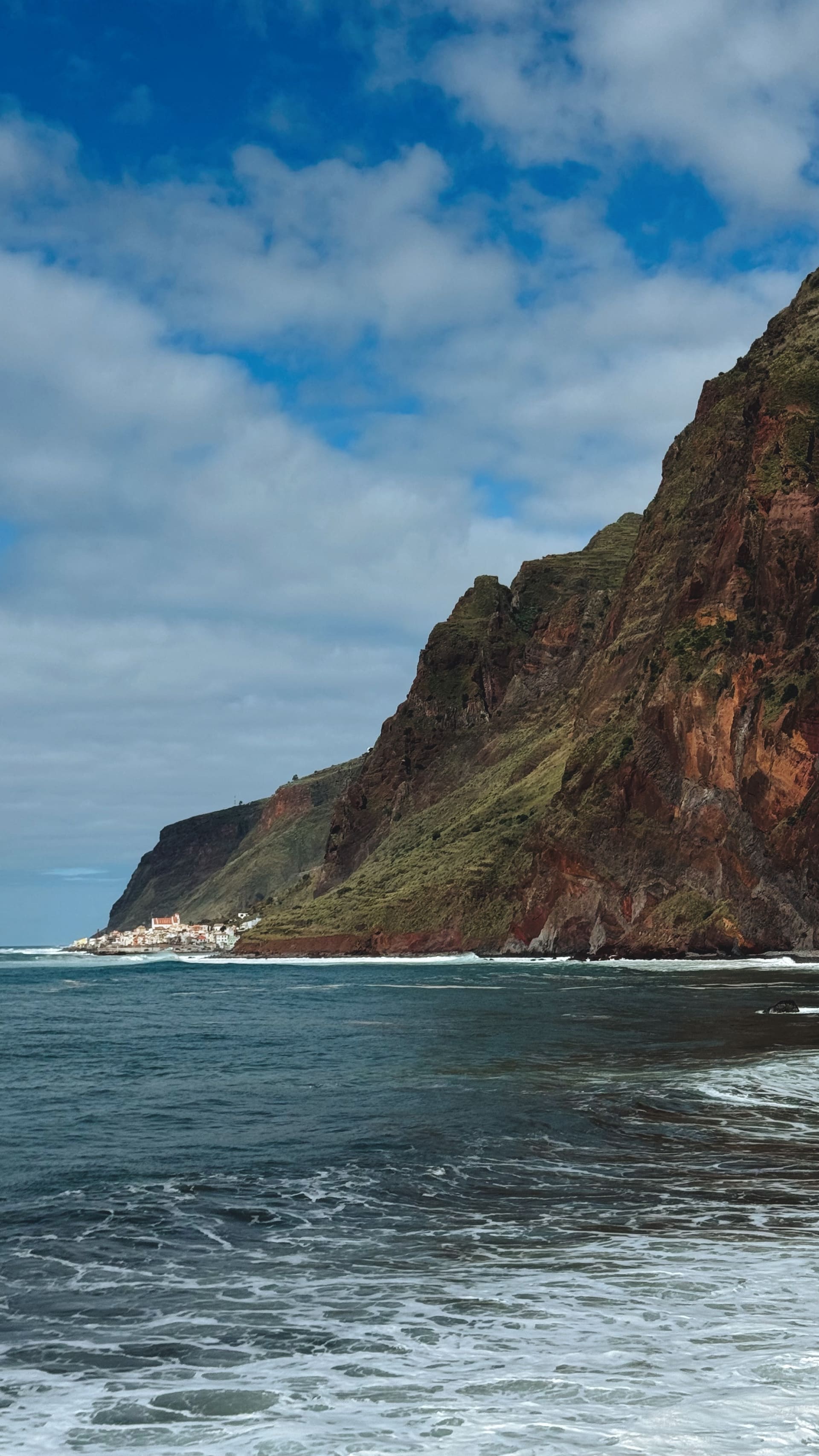 Coastal cliffs meeting a village by the sea on Madeira, photographed by the EARTH founders.