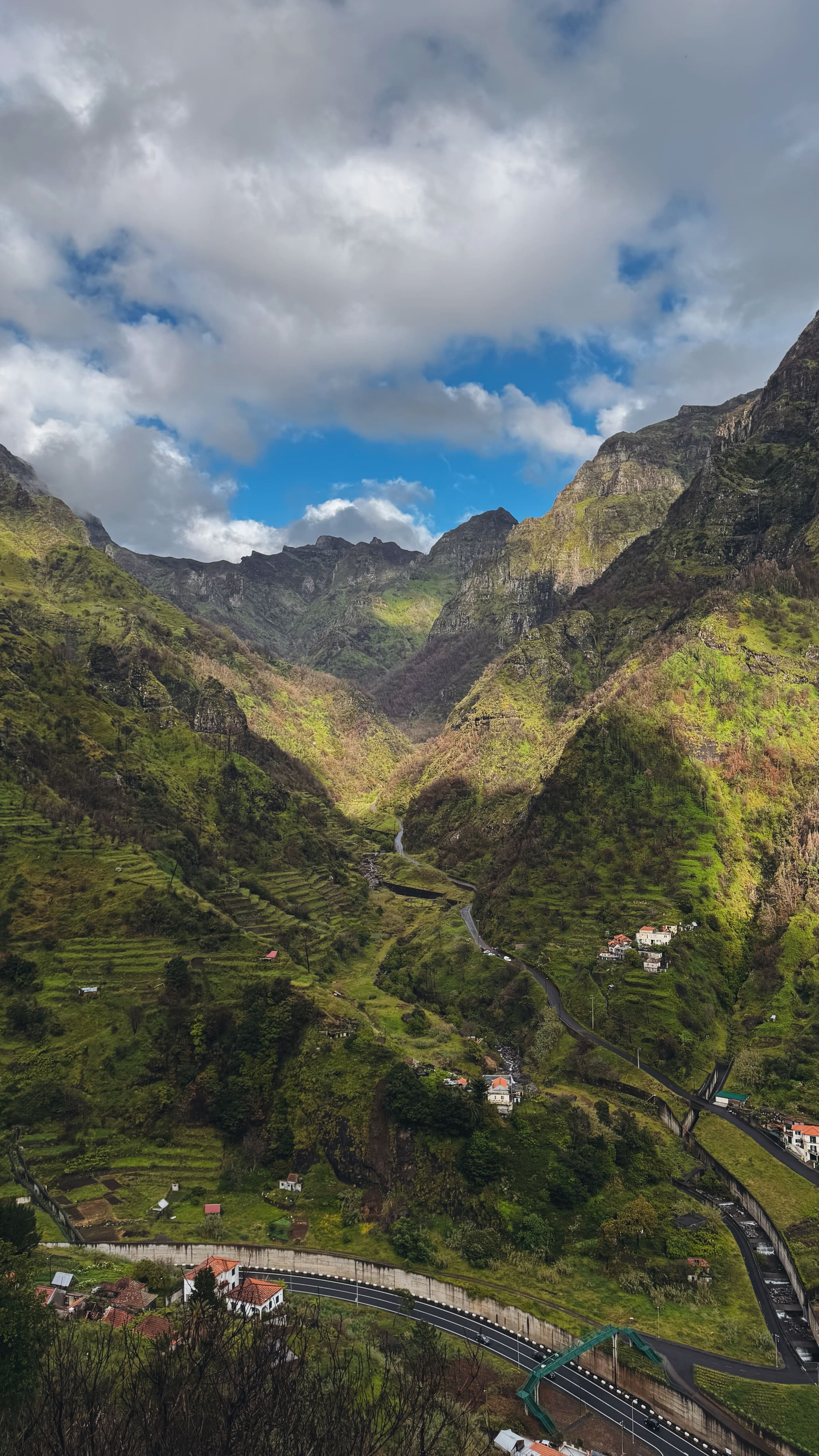 A deep green valley with a village and winding mountain road, photographed by the EARTH founders.