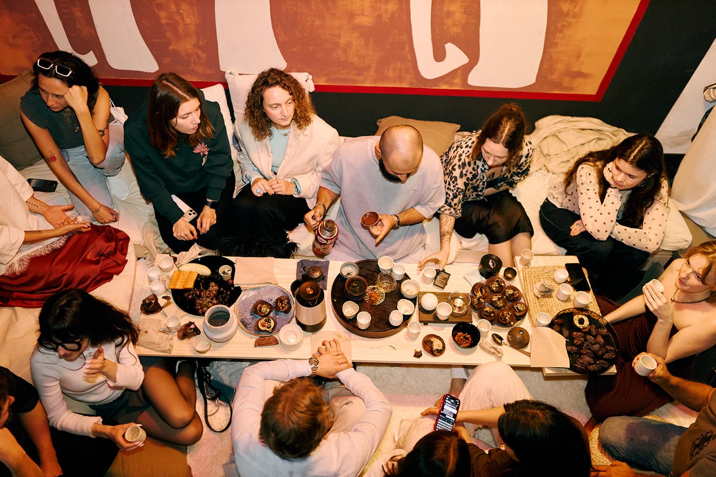 A shared tea ceremony gathering, cups and sweets laid out around a low table, hosted by EARTH.